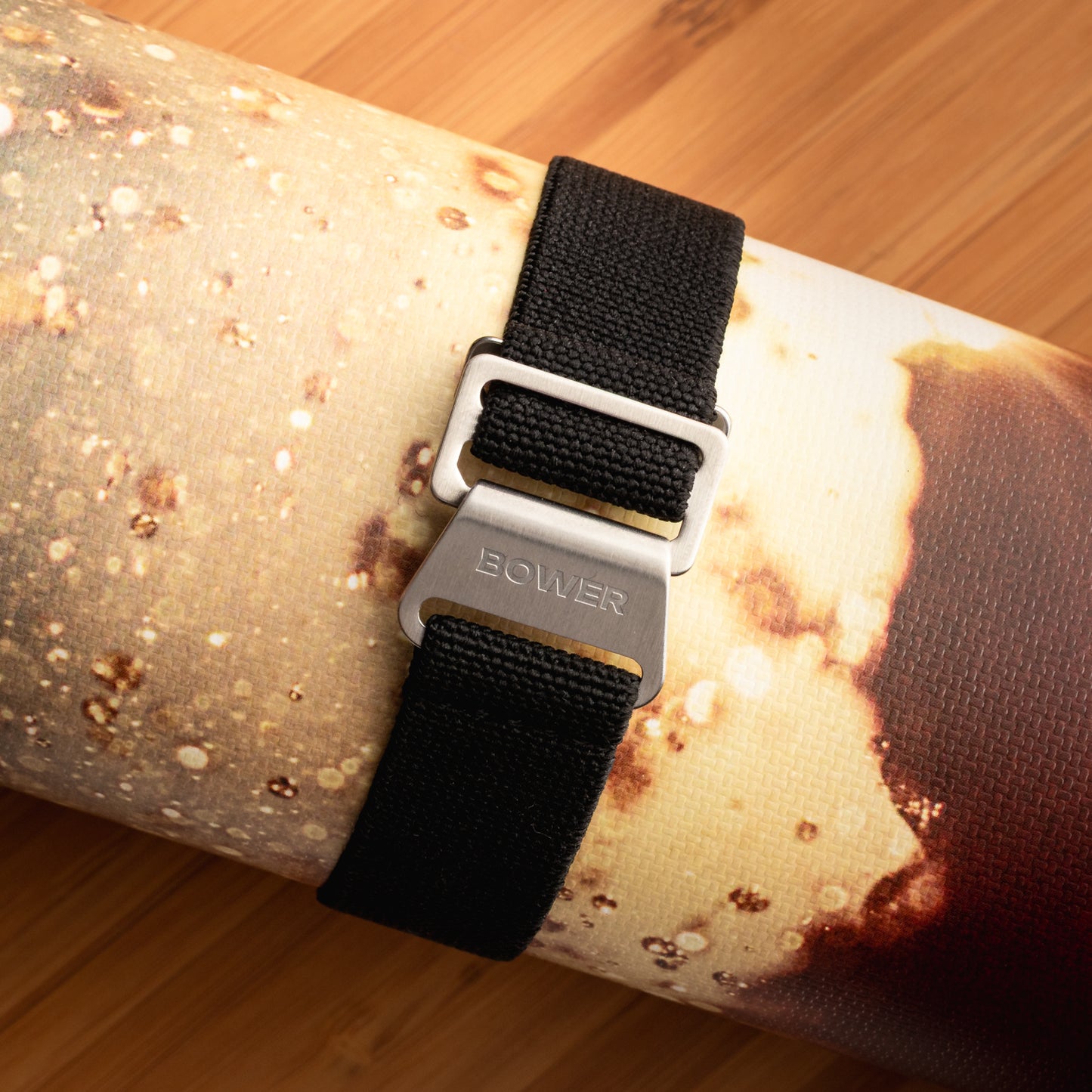 Black nylon watch strap by Bower with brushed stainless steel clasp, wrapped around a textured surface with ocean imagery. Rugged strap designed for outdoor and marine use.
