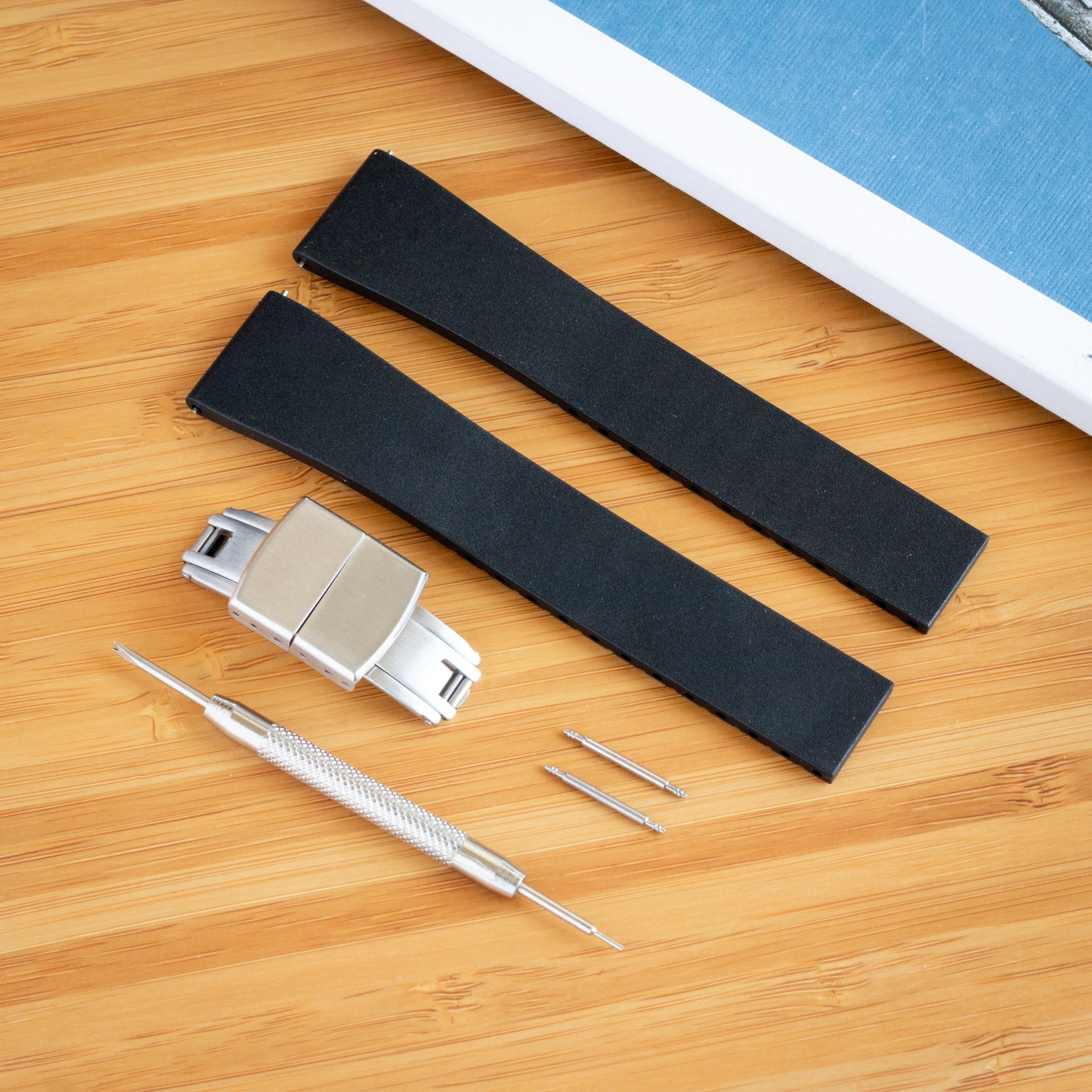 Black watch CTS FKM strap with metal clasp and tools on a wooden surface