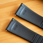 Two black CTS FKM Rubber straps with  on a wooden surface