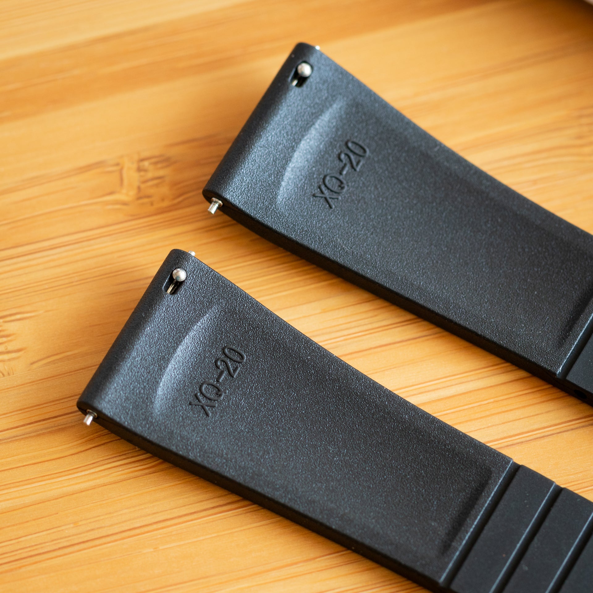 Two black CTS FKM Rubber straps with  on a wooden surface