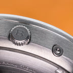 Macro shot of the engraved crown, recessed tide pusher and screw-down caseback edge on the Bower Tide Seeker watch, highlighting precision-machined stainless steel detailing against a warm background.